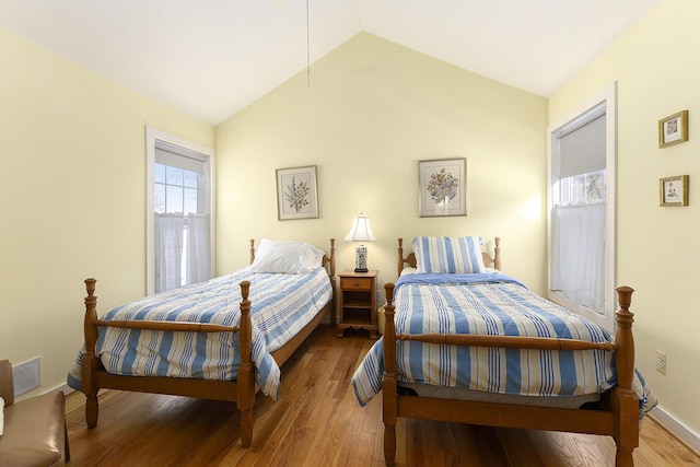 bedroom featuring vaulted ceiling, wood finished floors, visible vents, and baseboards