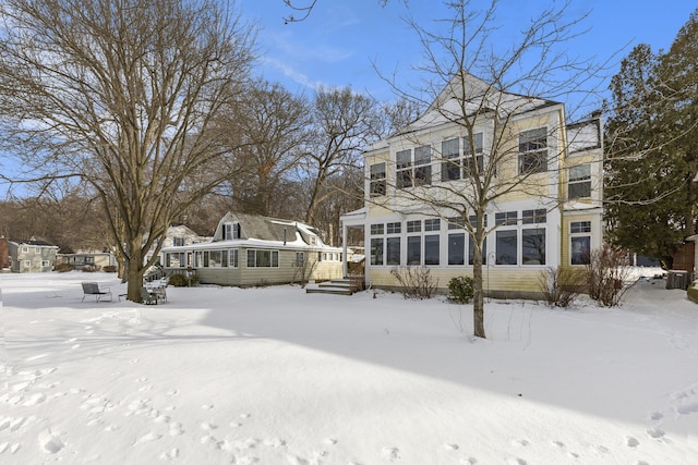 snow covered house featuring a sunroom