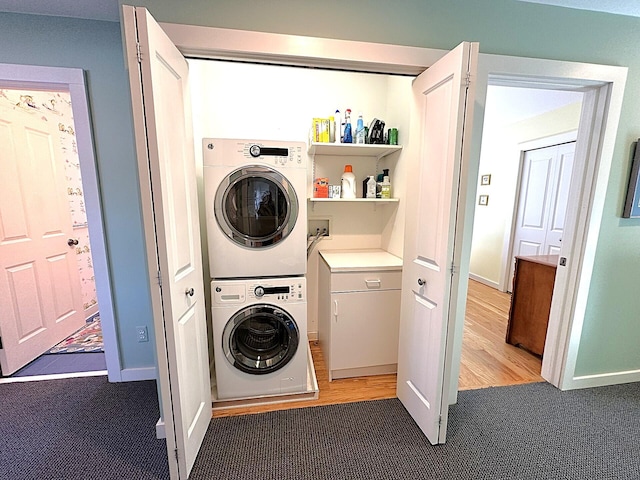 laundry room with laundry area, carpet, baseboards, and stacked washer / dryer