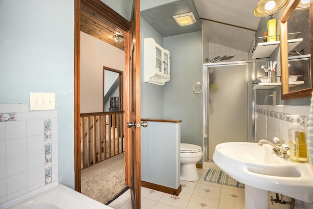 full bath featuring tile patterned flooring, toilet, a sink, tile walls, and a shower stall