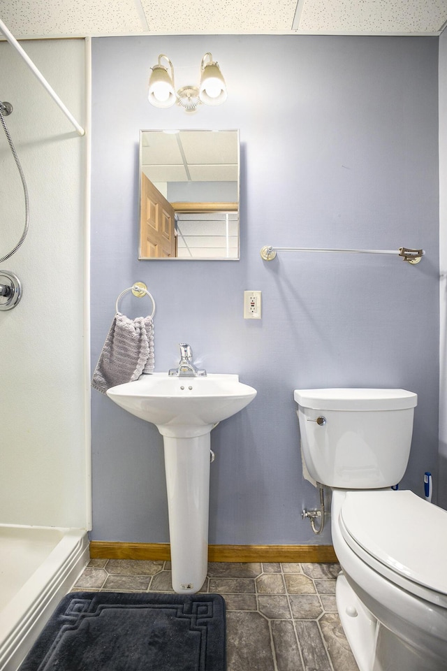 bathroom with toilet, a paneled ceiling, and baseboards