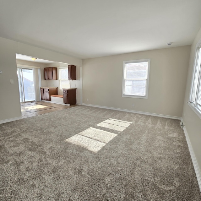 unfurnished living room featuring carpet floors and baseboards