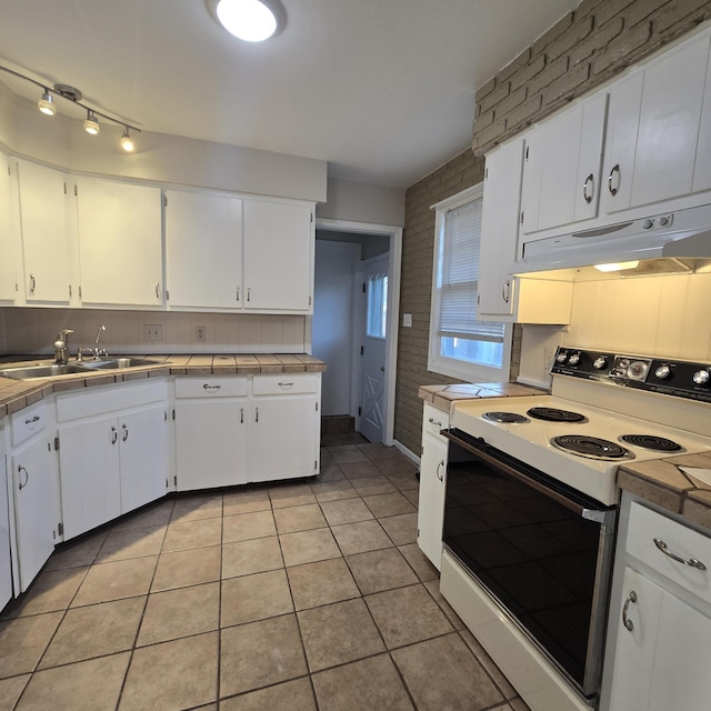 kitchen featuring tile countertops, under cabinet range hood, white electric range, a sink, and white cabinetry