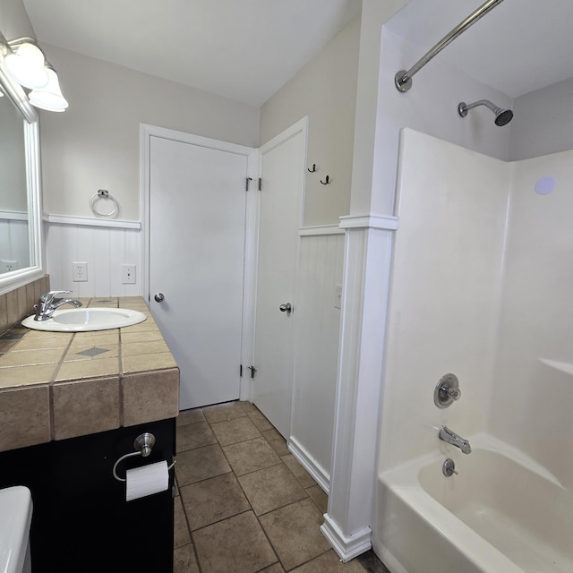 full bathroom with tile patterned flooring, bathtub / shower combination, a wainscoted wall, and vanity