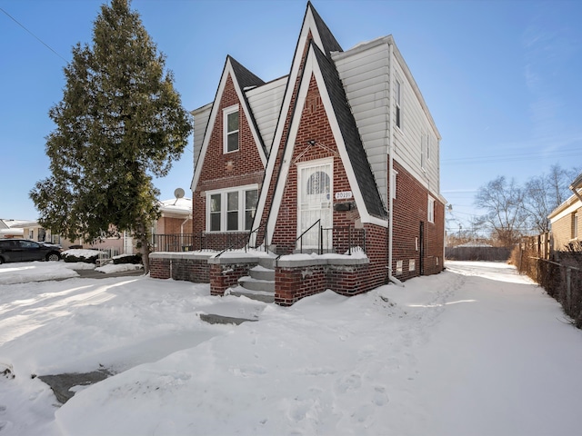 english style home with brick siding and fence