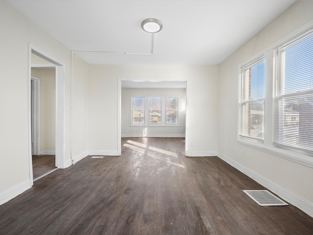 interior space with dark wood-style floors, visible vents, and baseboards