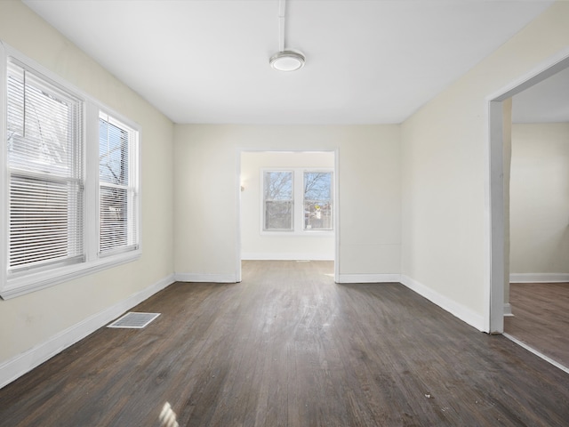 interior space featuring dark wood-style floors, visible vents, and baseboards