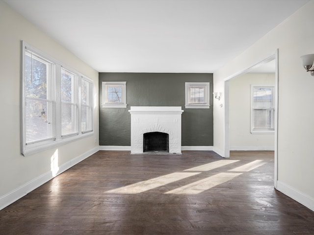 unfurnished living room with a brick fireplace, baseboards, and dark wood finished floors