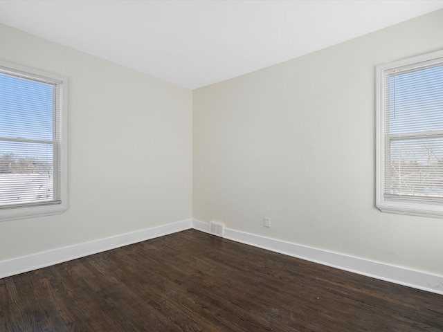 unfurnished room with wood finished floors, visible vents, and baseboards