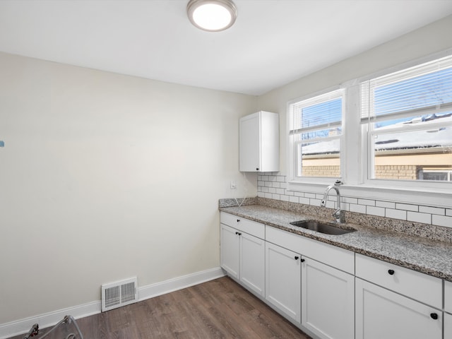 kitchen featuring stone countertops, white cabinets, a sink, and visible vents