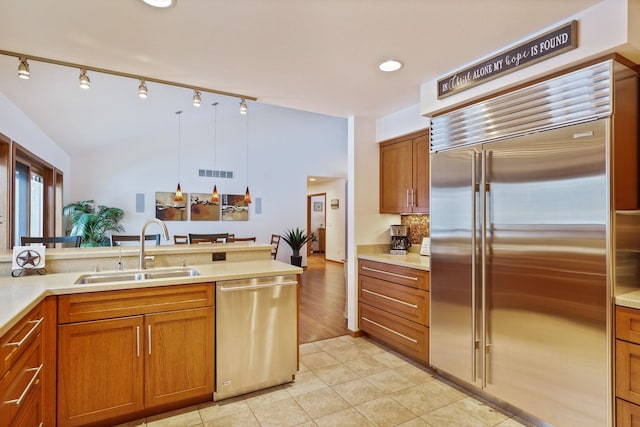 kitchen featuring stainless steel appliances, a sink, visible vents, light countertops, and brown cabinetry