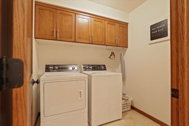 clothes washing area featuring cabinet space, light tile patterned floors, baseboards, and washer and clothes dryer