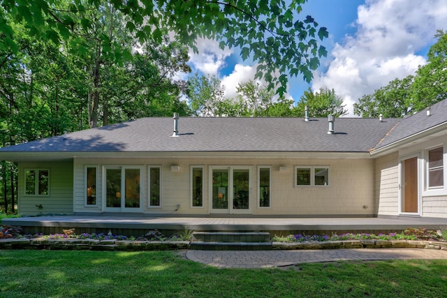 rear view of property with a yard and roof with shingles