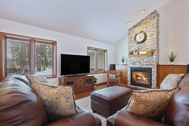 living room with lofted ceiling, a stone fireplace, and wood finished floors