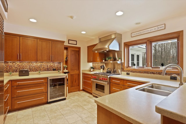 kitchen featuring beverage cooler, a sink, exhaust hood, light countertops, and luxury range