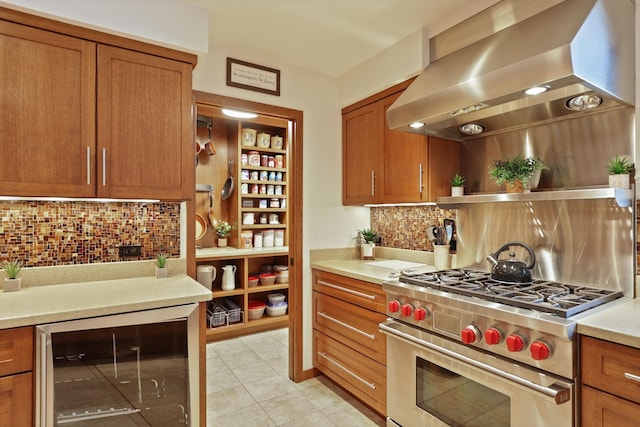 kitchen featuring wine cooler, light countertops, ventilation hood, high end stainless steel range, and brown cabinets