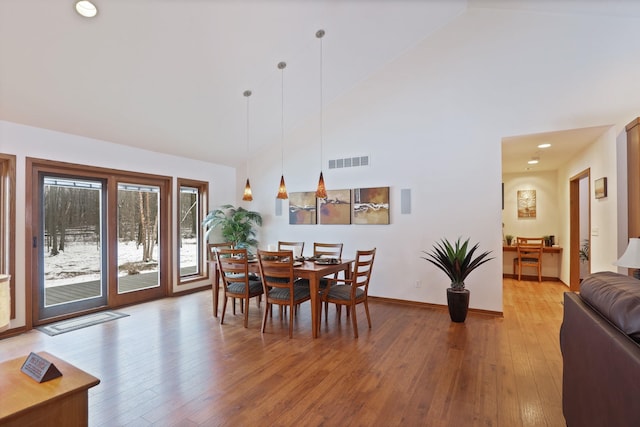 dining room with high vaulted ceiling, visible vents, and wood finished floors