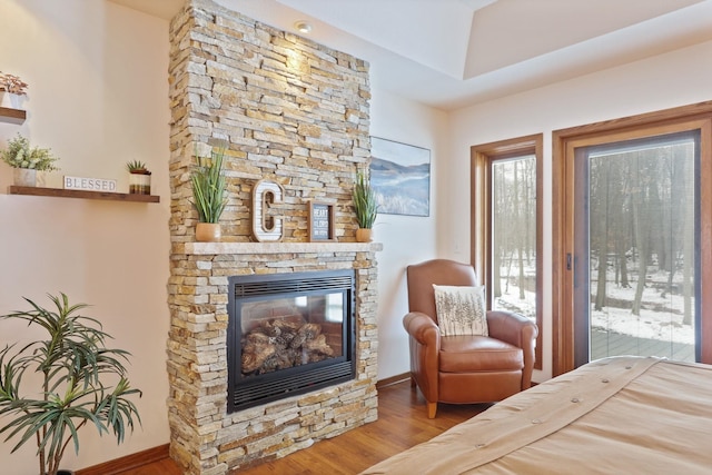 bedroom with a stone fireplace and wood finished floors