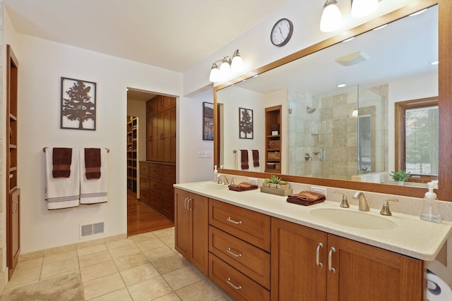 bathroom with double vanity, visible vents, a spacious closet, a stall shower, and a sink