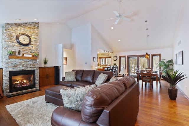 living room featuring high vaulted ceiling, a ceiling fan, a fireplace, and wood finished floors