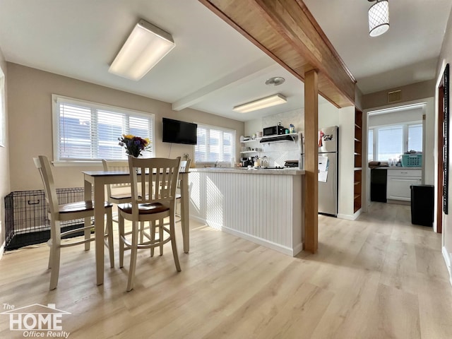 dining space with beamed ceiling, light wood-type flooring, and visible vents