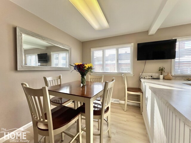 dining room with beamed ceiling, a wealth of natural light, and baseboards