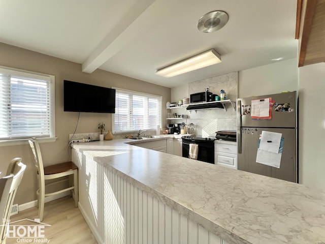 kitchen featuring light wood finished floors, light countertops, black appliances, open shelves, and backsplash