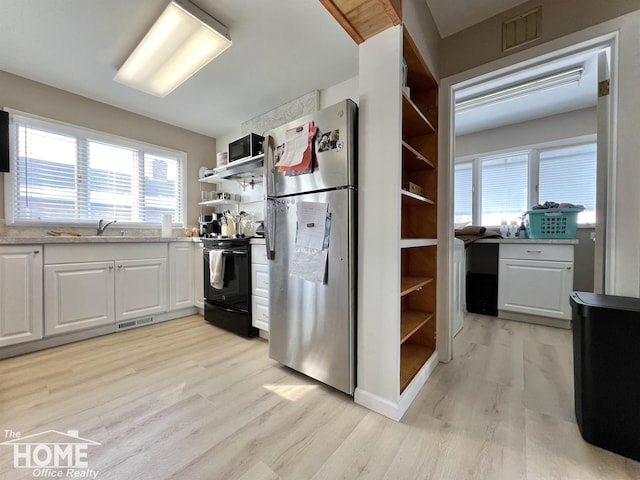 kitchen featuring white cabinets, light countertops, freestanding refrigerator, black electric range oven, and open shelves