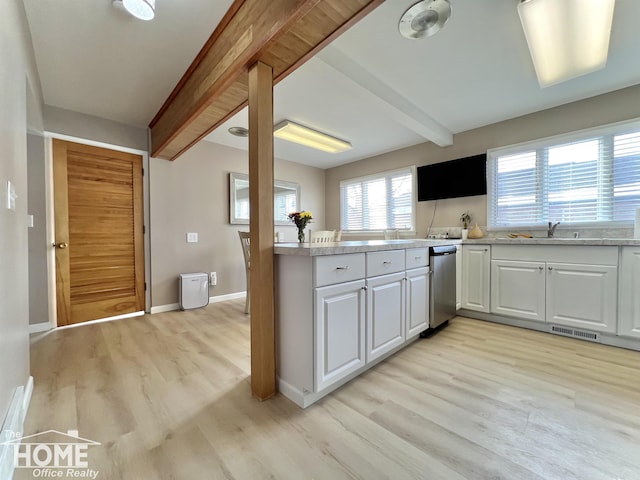 kitchen with baseboards, white cabinets, light countertops, light wood-type flooring, and beam ceiling