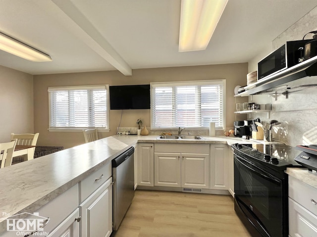 kitchen featuring appliances with stainless steel finishes, white cabinets, light countertops, and a sink