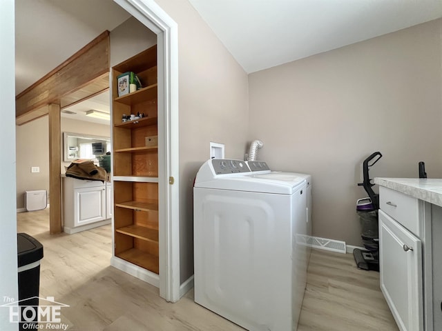 clothes washing area featuring light wood-type flooring, cabinet space, baseboards, and washer and clothes dryer