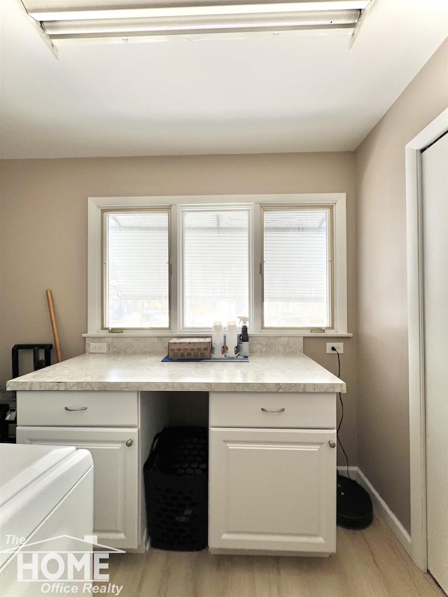 laundry room with light wood-style floors, cabinet space, and baseboards