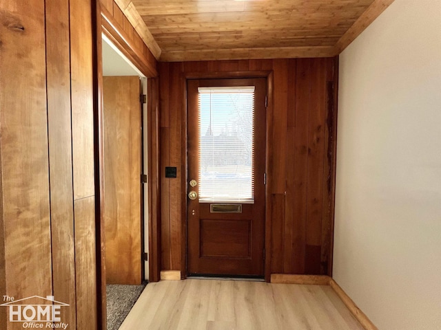 doorway to outside featuring light wood-type flooring, wooden ceiling, and wooden walls