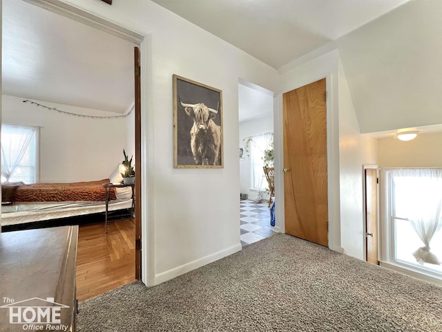 hallway featuring carpet and baseboards