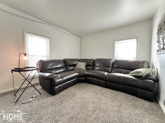 carpeted living area with lofted ceiling and baseboards