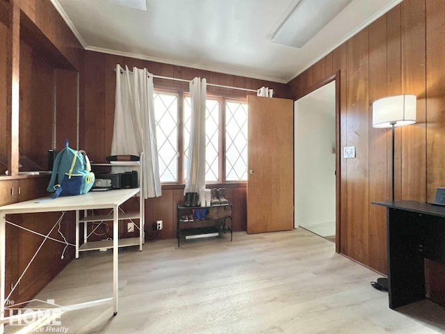 office space with light wood-style floors, crown molding, and wood walls