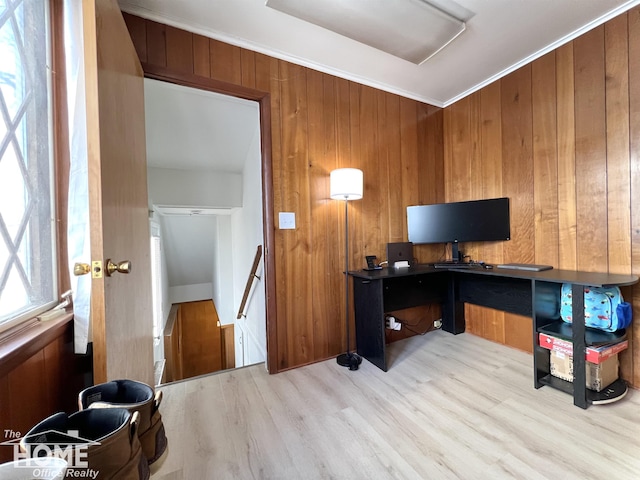 home office featuring light wood-style floors, ornamental molding, and wood walls