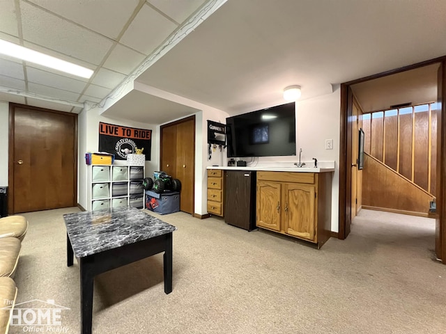 living area with a paneled ceiling and light colored carpet