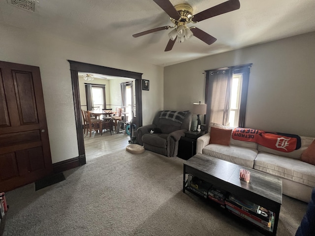 living area featuring light carpet, ceiling fan, and visible vents