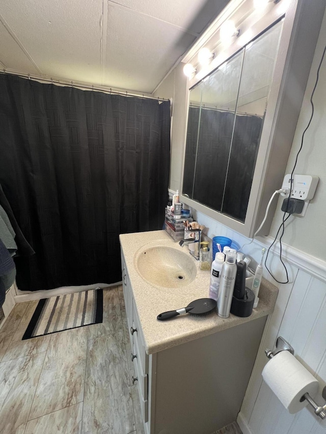 bathroom featuring a wainscoted wall, vanity, and a textured ceiling