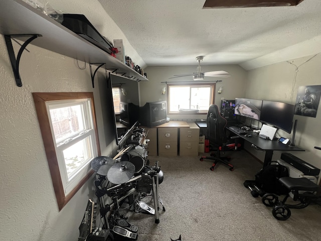 carpeted home office with a textured wall, vaulted ceiling, a textured ceiling, and a ceiling fan