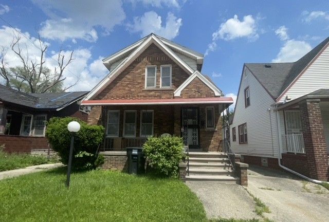 view of front facade with a porch, a front yard, and brick siding