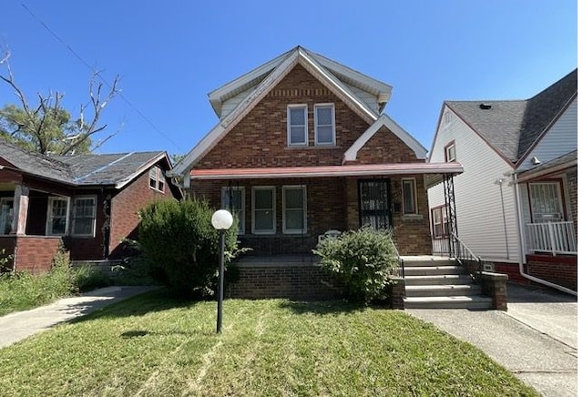 view of front of house with a front lawn, a porch, and brick siding