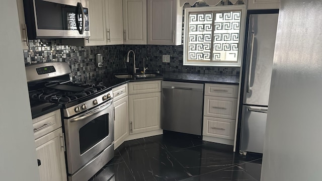 kitchen featuring marble finish floor, tasteful backsplash, dark countertops, appliances with stainless steel finishes, and a sink