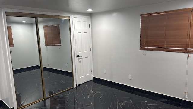 unfurnished bedroom featuring marble finish floor, baseboards, a closet, and recessed lighting