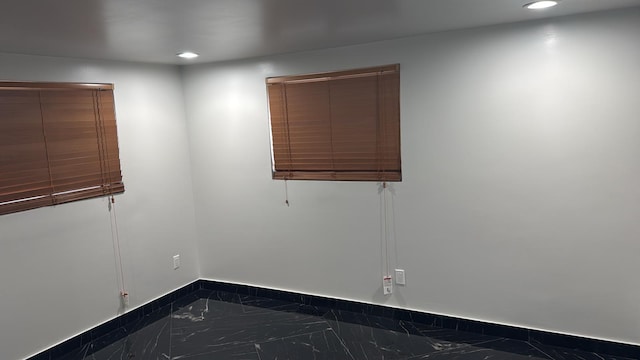 empty room featuring recessed lighting, marble finish floor, and baseboards