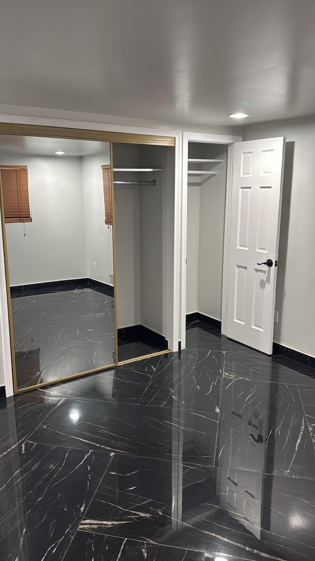 interior space with multiple closets, marble finish floor, and baseboards