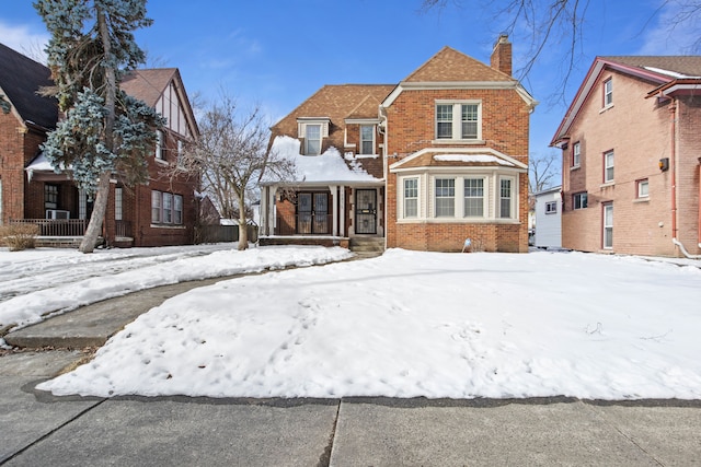 view of front of property with a shingled roof, a chimney, and brick siding