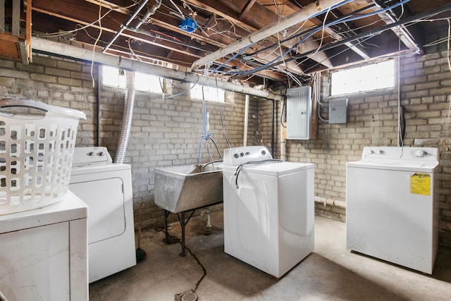 clothes washing area featuring laundry area, electric panel, washer and clothes dryer, and a sink