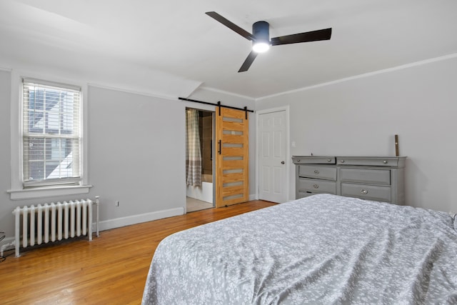 bedroom with a barn door, radiator heating unit, wood finished floors, and crown molding